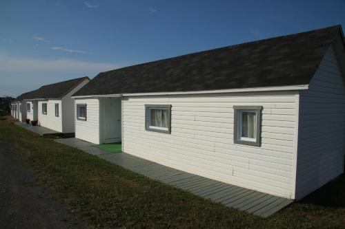 a row of white buildings with a row of windows at Les Cabines sur Mer in Cap-des-Rosiers