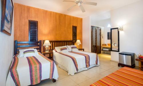 a hotel room with two beds and a television at Hotel Villas El Encanto Cozumel in Cozumel