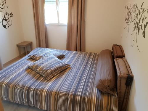 a bed in a bedroom with a striped bedspread at Gite Le Petit Pied-à-Terre in La Chapelle-Saint-Sauveur