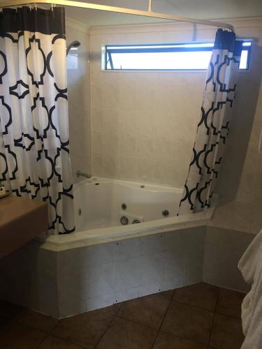 a bathroom with a tub and a shower curtain at Deco City Motor Lodge in Napier