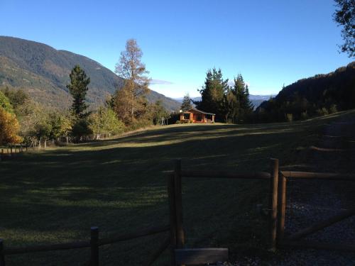 a fence in front of a field with a house at Murmullo de Arroyos in Caburgua