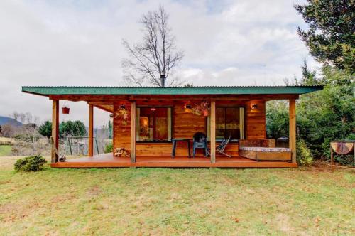 a small log cabin with a green roof at Murmullo de Arroyos in Caburgua