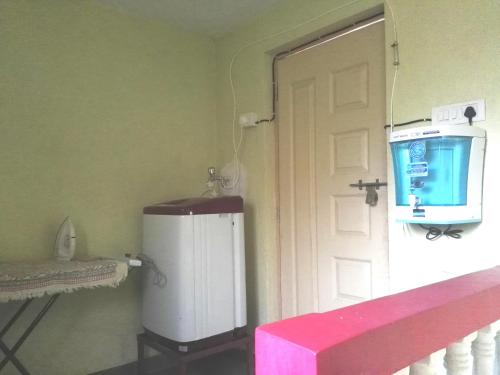 a small refrigerator in a room with a door at Thee Haven Candolim in Candolim