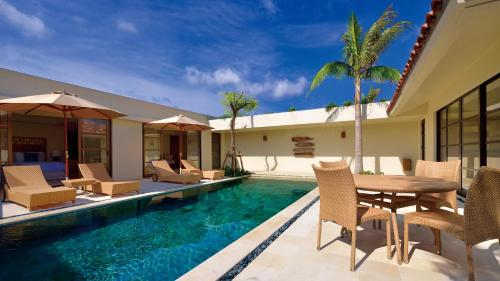 a patio with a table and chairs and a swimming pool at The Uza Terrace Beach Club Villas in Yomitan