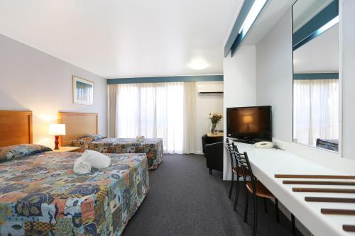 pokój hotelowy z łóżkiem i telewizorem z płaskim ekranem w obiekcie Reef Resort Motel w mieście Mackay