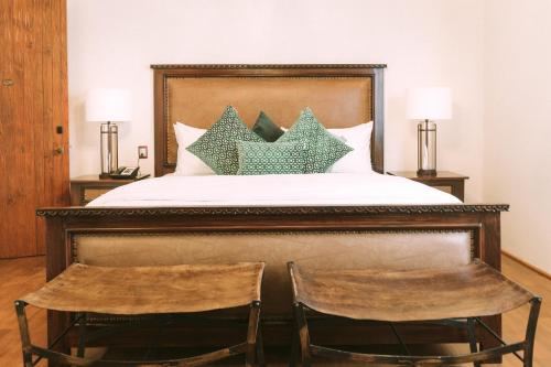 a bedroom with a bed with two chairs at Casona de los Sapos Hotel Boutique in Puebla