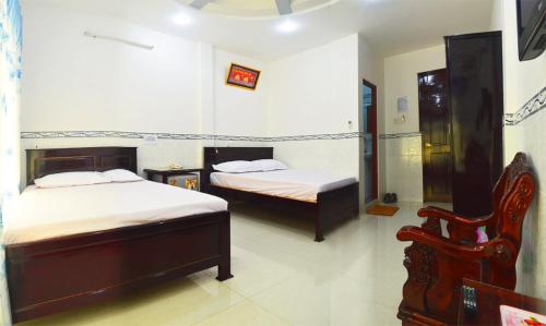 ein Schlafzimmer mit 2 Betten und einem Stuhl darin in der Unterkunft Phuong Hue Hotel in Soc Trang