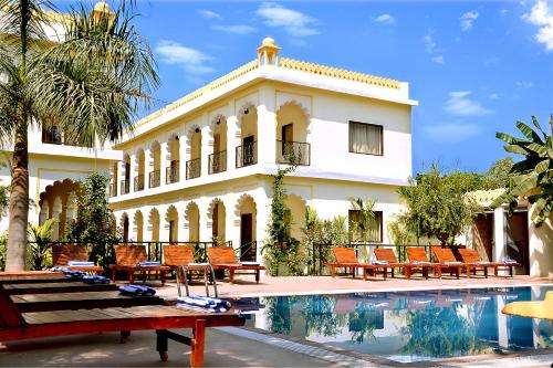 a building with a swimming pool in front of a house at Raj Palace Resort in Sawāi Mādhopur