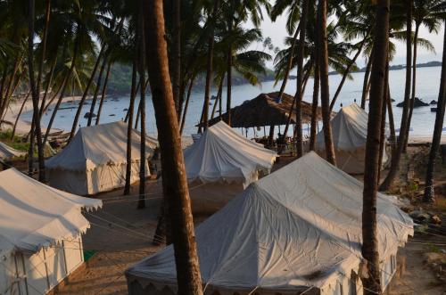 a group of tents on a beach with palm trees at Cola Beach Sunset Bay in Cola