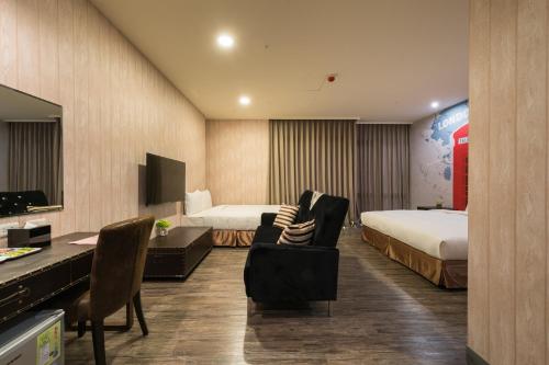 a hotel room with two beds and a desk at Skyone Hotel in Kaohsiung