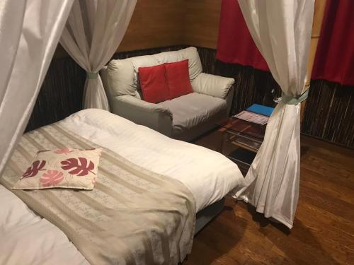 a bedroom with a bed and a chair with a red pillow at Hotel Vegas (Adult Only) in Sapporo