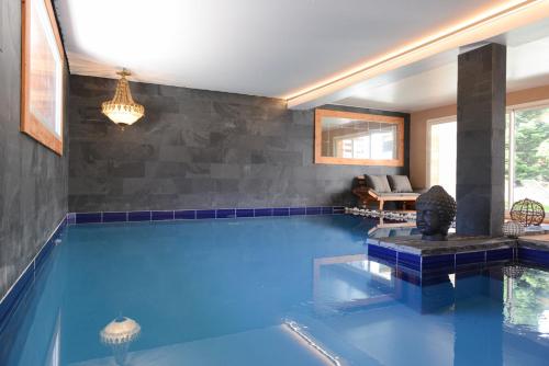 une grande piscine avec un mur carrelé bleu dans l'établissement La Maison Rapin, à Valloire