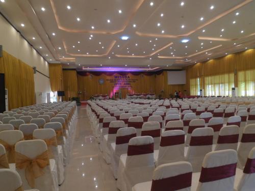 a large hall with rows of white chairs and a stage at Grand Madani Hotel in Mataram