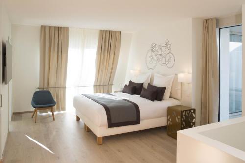 1 dormitorio blanco con 1 cama y 1 silla azul en The Passage - Urban Retreat, en Basilea