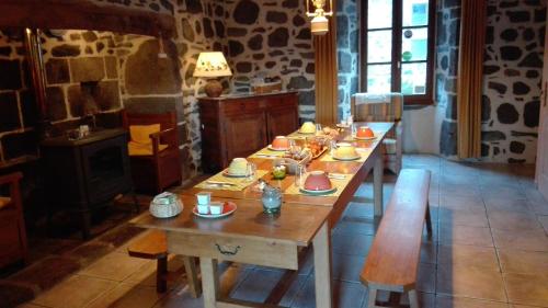 una gran mesa de madera con tazones y platos. en Chambre d'Hôtes La Maison de Barrouze, en Salers
