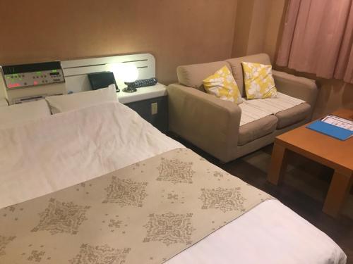 a small room with two beds and a couch at Hotel Vegas (Adult Only) in Sapporo
