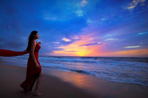 a woman in a red dress standing on the beach at Indriya Sands in Cherai Beach