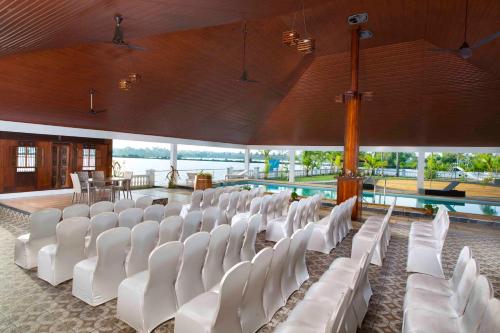 a row of white chairs in a room with a pool at Indriya Sands in Cherai Beach