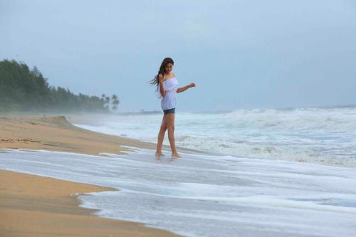a woman standing in the water on the beach at Indriya Sands in Cherai Beach
