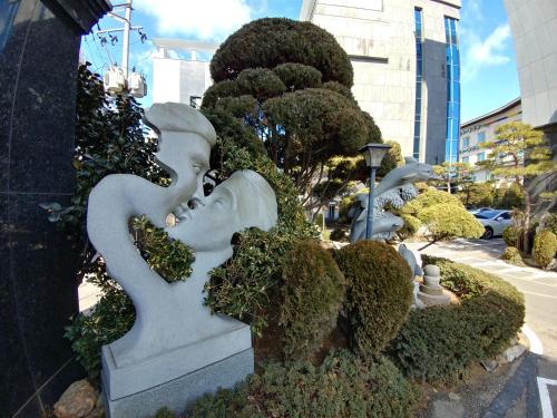 a garden with statues and bushes on a street at Seosan Aria Hotel in Seosan