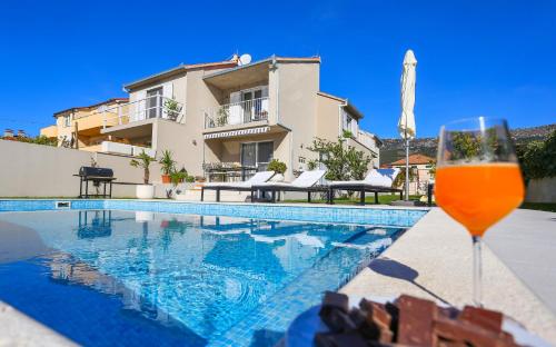 a glass of beer next to a swimming pool at Villa Elysium - Family House with Heated Pool in Kaštela