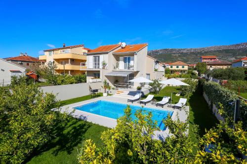 a villa with a swimming pool and a house at Villa Elysium - Family House with Heated Pool in Kaštela