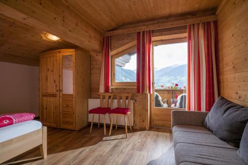 Zimmer mit einem Bett, einem Sofa und einem Fenster in der Unterkunft Hausers Ferienwohnungen in Zell am Ziller