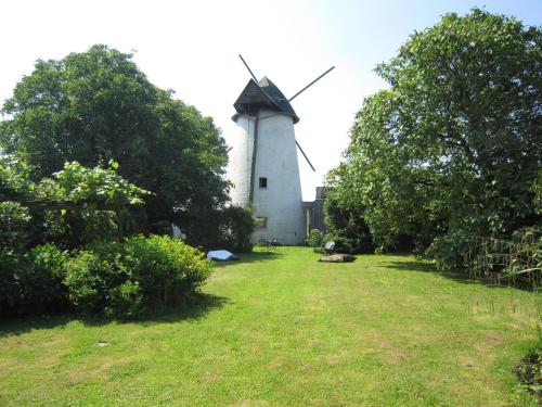 a windmill in the middle of a field with trees at home in the Flemish Ardennes between the meadows in Sint-Kornelis-Horebeke