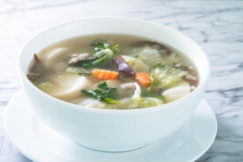 a white bowl of soup on a white plate at P Plus Hotel in Pattaya Central