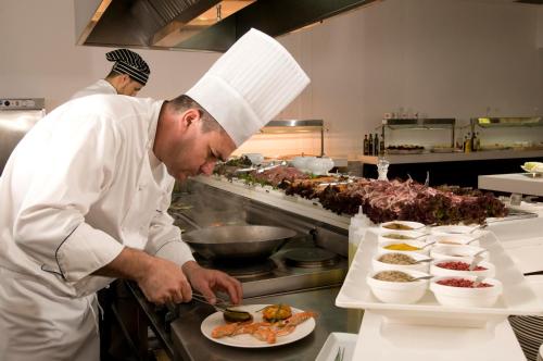 a chef preparing a plate of food in a kitchen at Las Gaviotas Suites Hotel & Spa in Playa de Muro