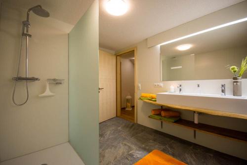 a bathroom with a sink and a shower and a mirror at Ferienwohnung Schrofamühli in Silbertal