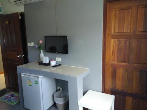 a room with a refrigerator and a tv on a wall at Kohkaew Village 2@Kohsamet in Ko Samed