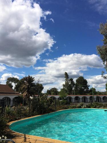 a swimming pool with a blue sky and clouds at Azalea Motel in Coonabarabran