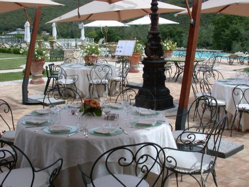 a group of tables and chairs with white tables and umbrellas at Tenuta Del Gallo in Amelia