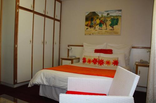 Blue Mountain Inn Lesotho في Teyateyaneng: غرفة نوم بسرير وكرسي أبيض