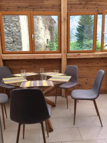 une salle à manger avec une table, des chaises et des fenêtres dans l'établissement Riders Apartments, au Bourg-dʼOisans