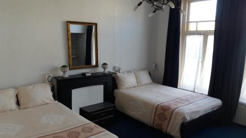 1 dormitorio con 2 camas, espejo y ventana en All-In Hotel en Den Bosch