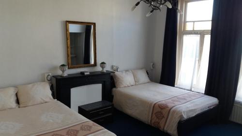 Un dormitorio con dos camas y un espejo y una ventana. en All-In Hotel, en Den Bosch