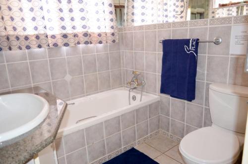 a bathroom with a toilet and a tub and a sink at Summer Place Umzumbe in Umzumbe
