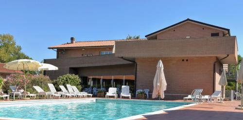 - une piscine avec des chaises et des parasols à côté d'un bâtiment dans l'établissement Residence San Rossore, à Pise