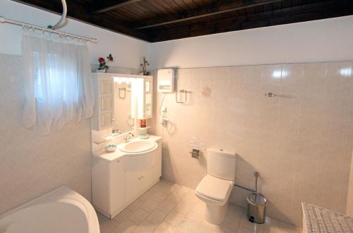 a white bathroom with a toilet and a sink at Sweet Memories Beach Houses in Mesongi