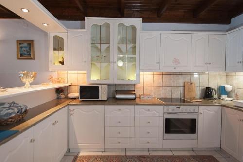a white kitchen with white cabinets and a microwave at Sweet Memories Beach Houses in Mesongi