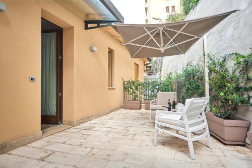 a patio with two chairs and an umbrella at Domus Il Palio in Siena