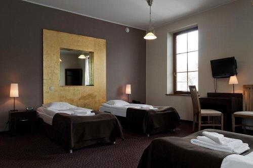 ein Hotelzimmer mit 3 Betten und einem Spiegel in der Unterkunft A' PROPOS Hotel, Restauracja, Club in Wałbrzych
