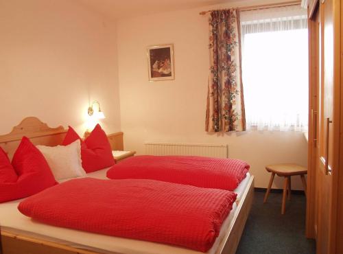 a bedroom with two beds with red pillows and a window at Haus Elfi in Wagrain