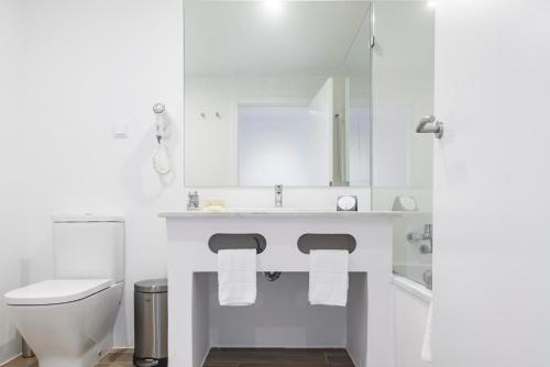 a white bathroom with a toilet and a sink at MH Atlantico in Peniche