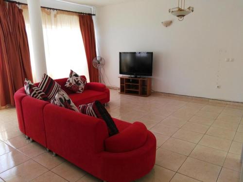 a living room with two red couches and a television at Casa da Luz - Appartement in Mindelo