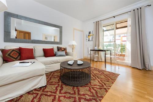 uma sala de estar com um sofá branco e uma mesa em Genteel Home Vinuesa em Sevilha
