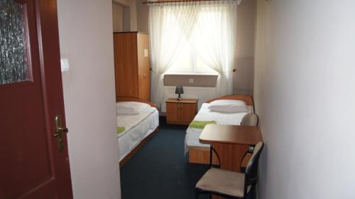 a room with two beds and a table and a window at Zajazd Fadom in Łomża