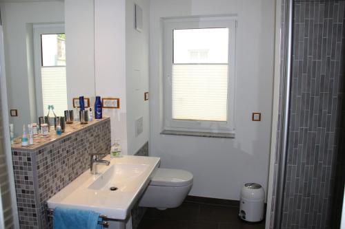 ein Bad mit einem Waschbecken, einem WC und einem Fenster in der Unterkunft Villa Gutenberg in Binz